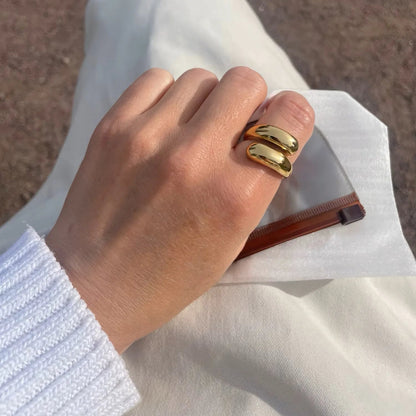 Hand with gold nail polish holding a transparent clutch against a neutral background