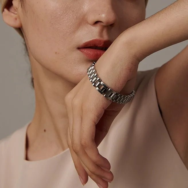 Close-up of a person wearing a silver bracelet on a neutral background