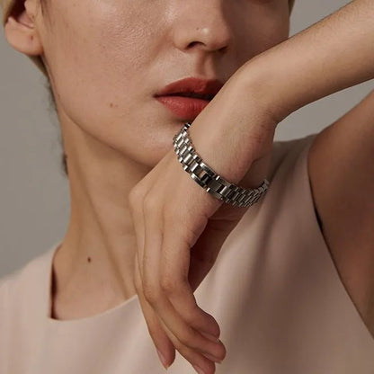 Close-up of a person wearing a silver bracelet on a neutral background