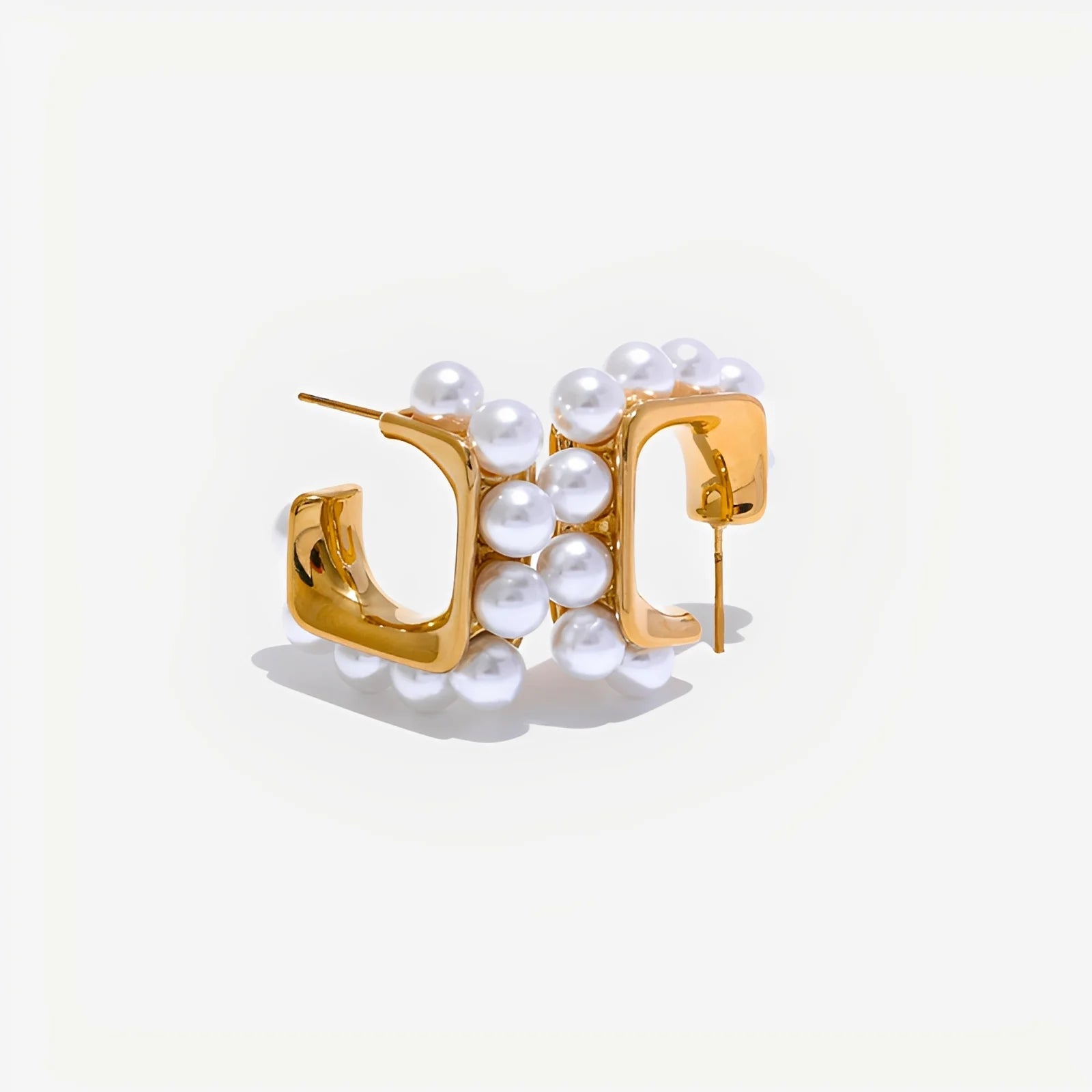 Gold hoop earrings with pearl accents on a light gray background