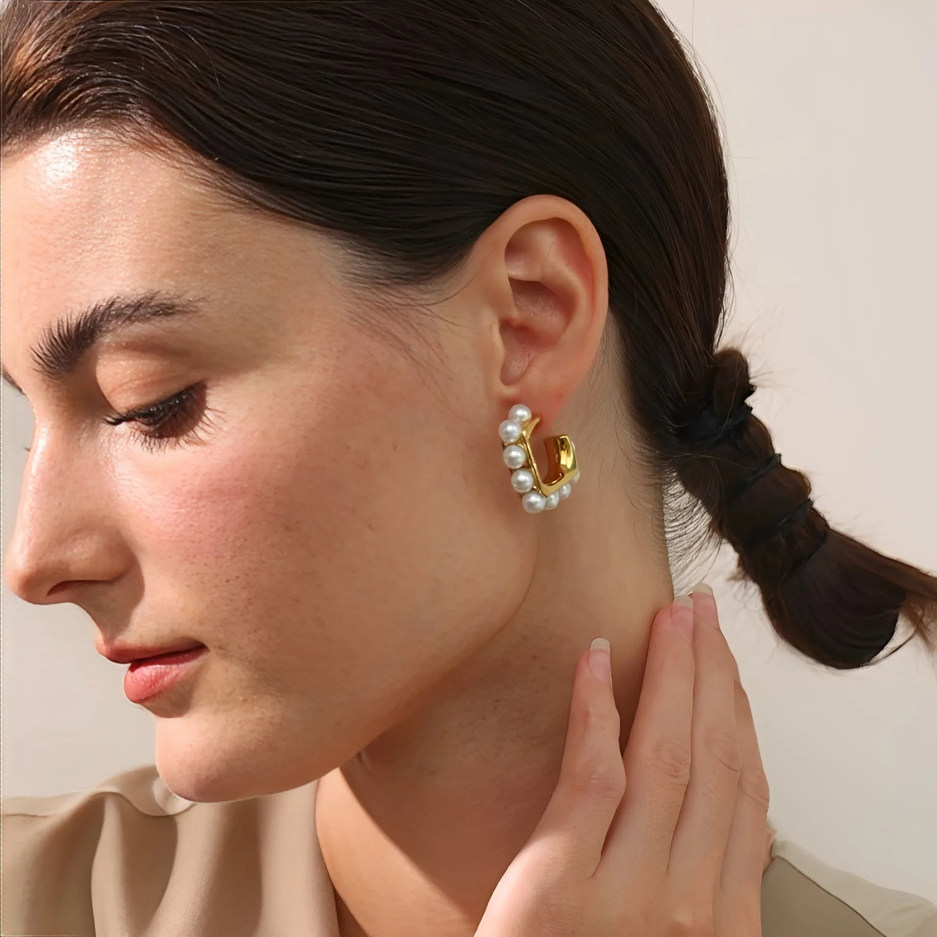 Close-up of a woman wearing a gold earring with pearls.