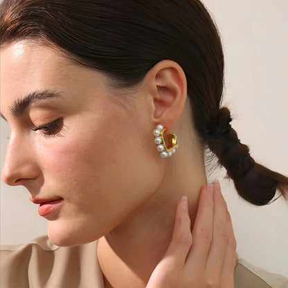 Close-up of a woman wearing a gold earring with pearls.