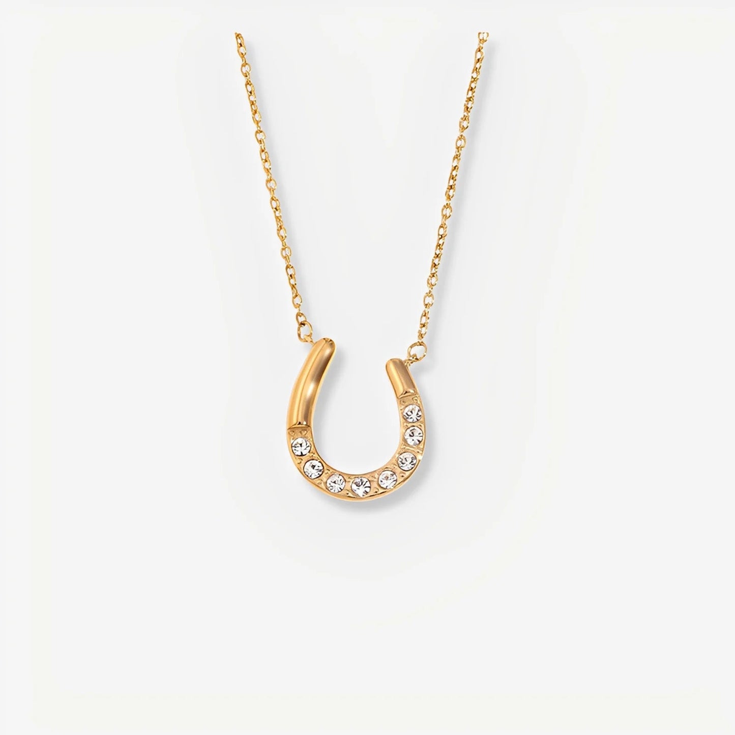 Gold horseshoe necklace with crystals on a white background