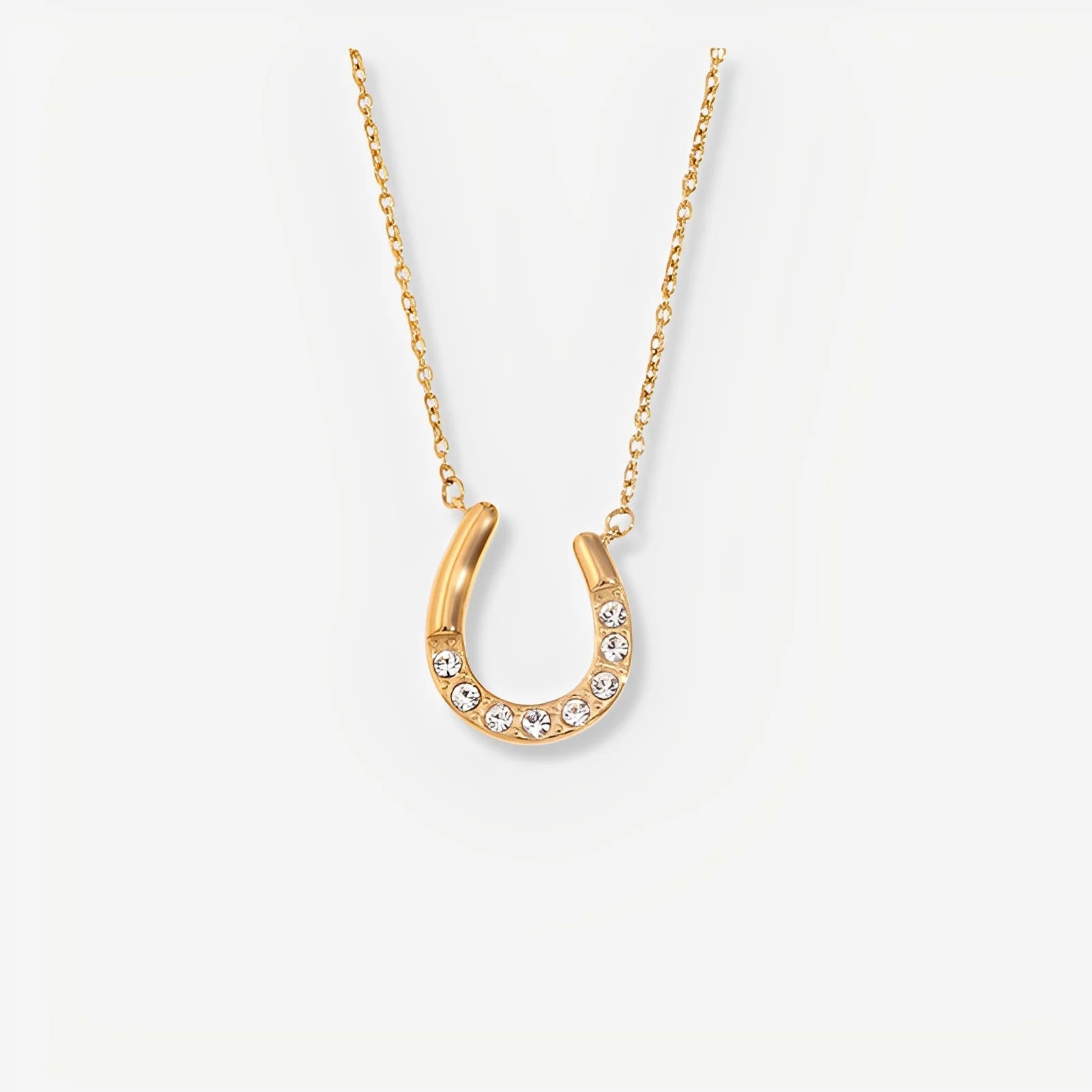 Gold horseshoe necklace with crystals on a white background