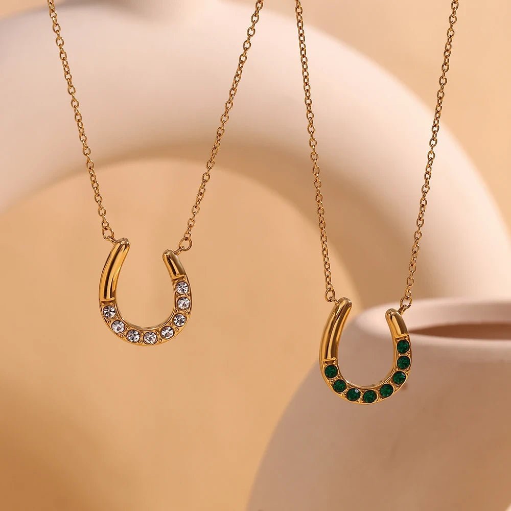 Two gold horseshoe necklaces with gemstones on a beige background