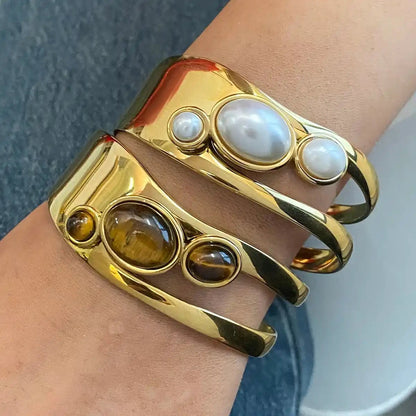Gold bracelet with embedded stones on a wrist against a neutral background
