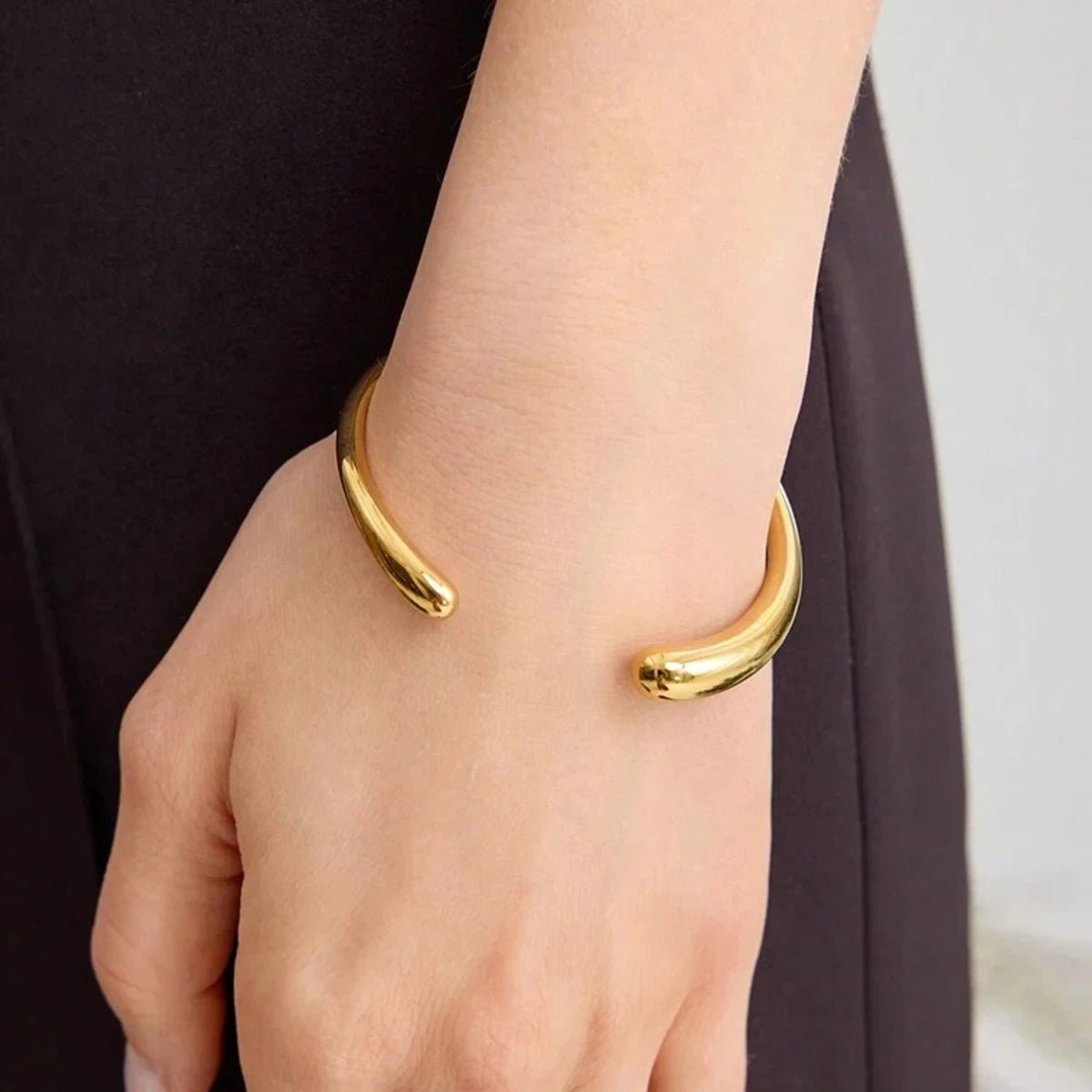 Gold bracelet on a wrist with a neutral background