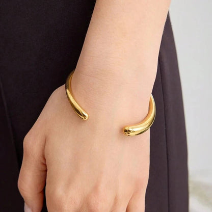 Gold bracelet on a wrist with a neutral background