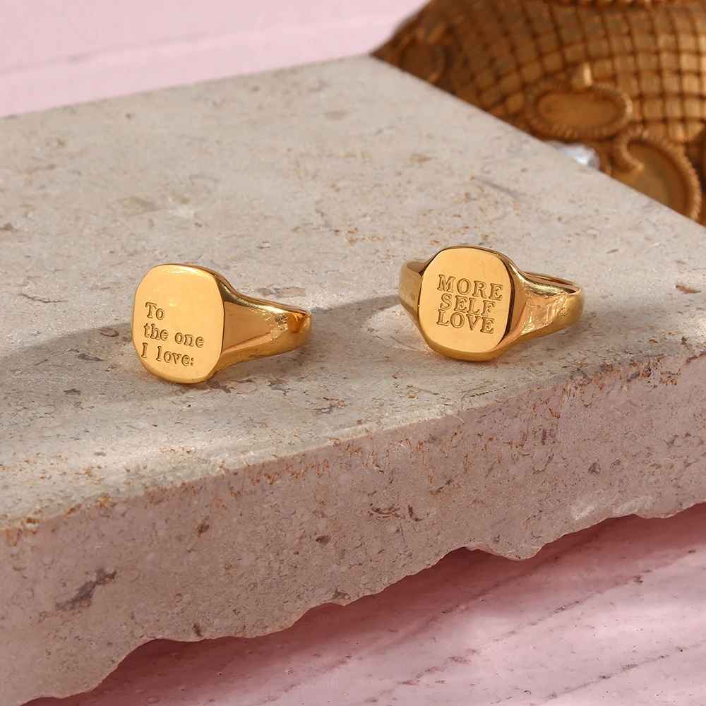 Two gold rings with engraved text on a stone surface