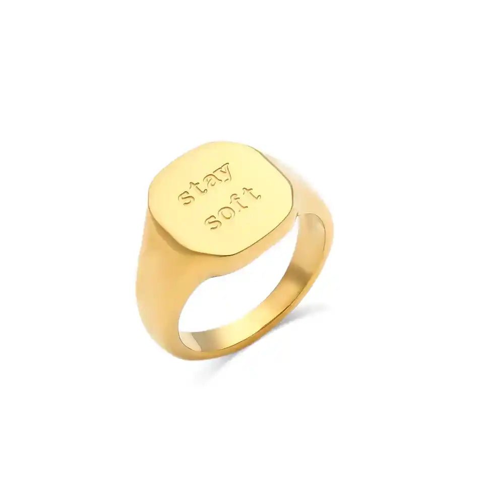 Gold ring with 'stay soft' engraving on a white background