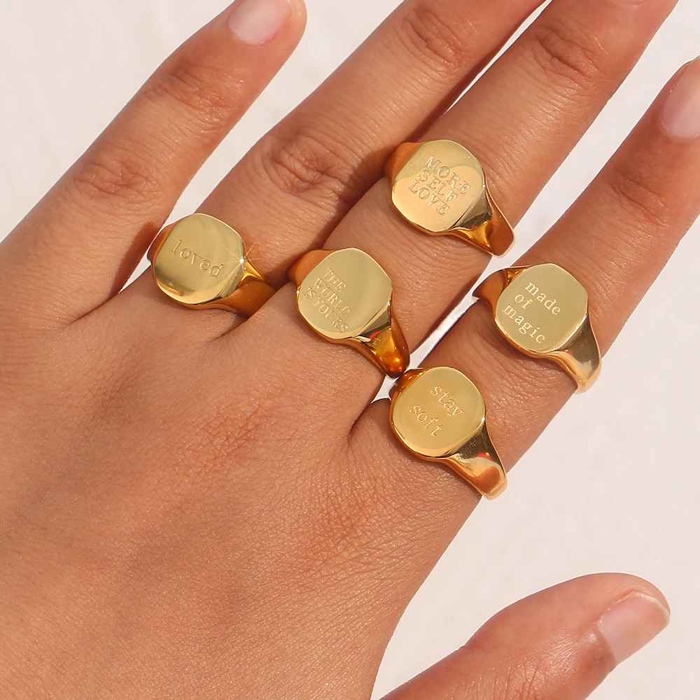 Gold rings with engraved text on a hand against a white background