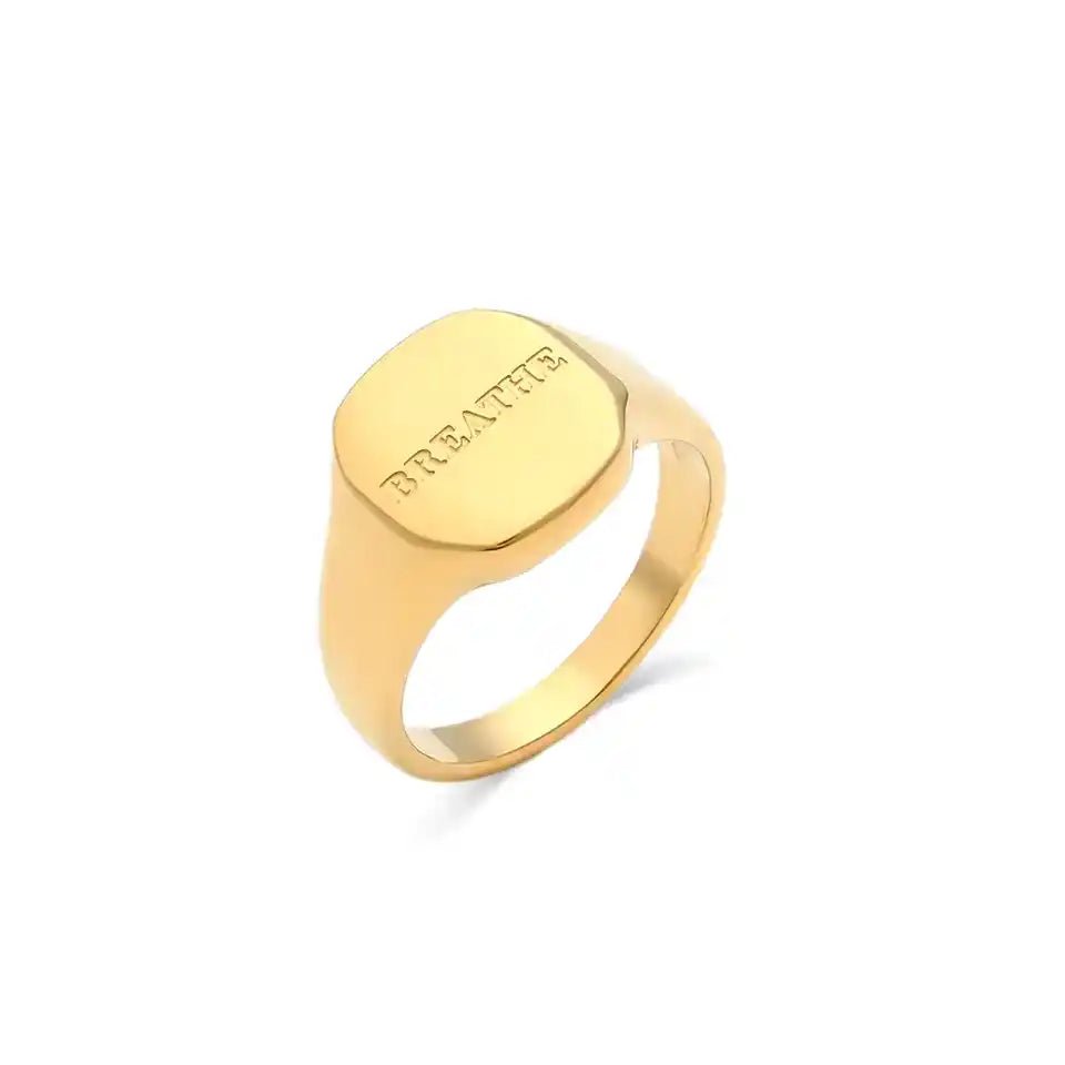 Gold ring with 'BRENTON' engraving on a white background