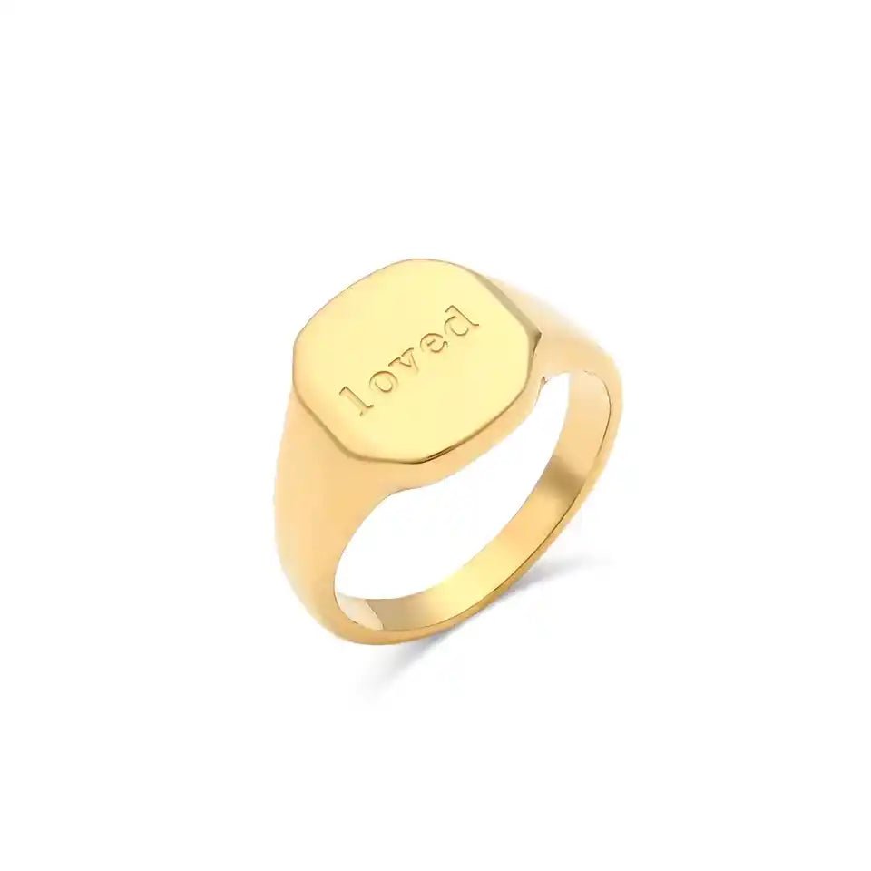 Gold ring with 'loved' engraving on a white background