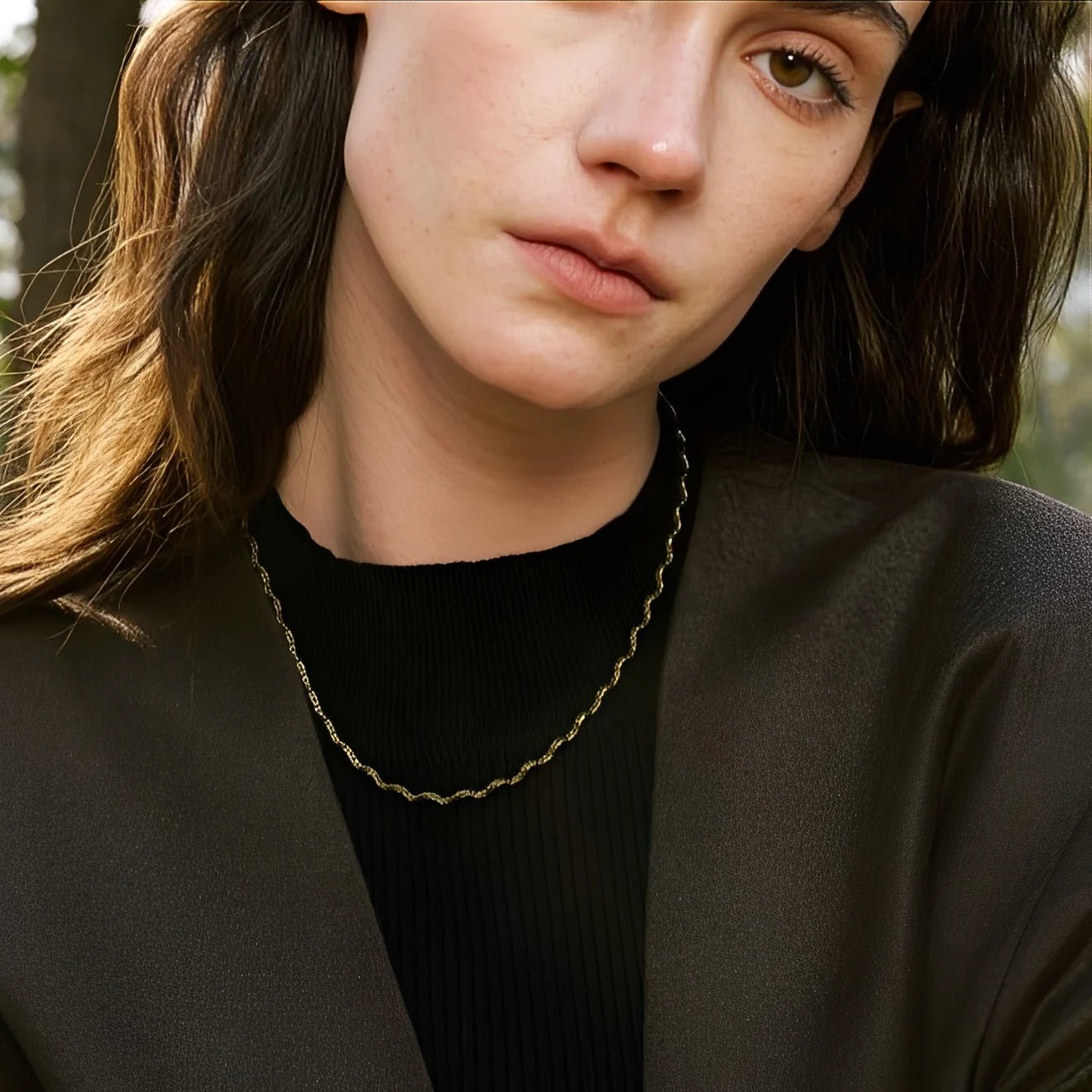 Close-up of a person wearing a gold chain necklace with a blurred background
