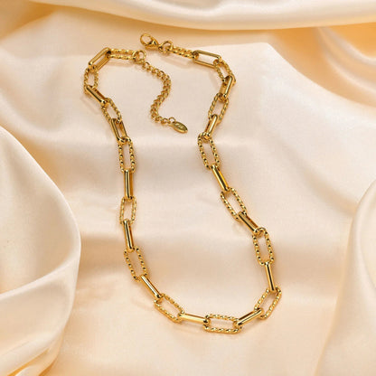 Gold chain necklace on a soft beige fabric background