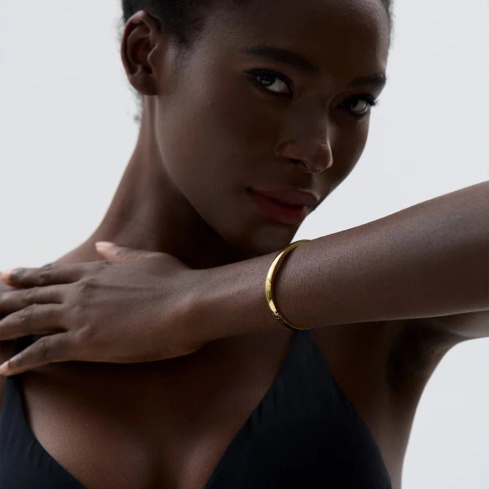 Woman wearing a gold bracelet on a plain background