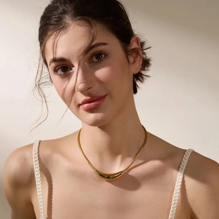 Woman wearing a gold necklace with a neutral background