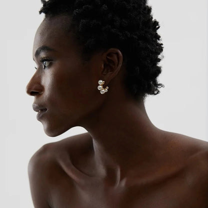 Woman wearing pearl earrings against a neutral background