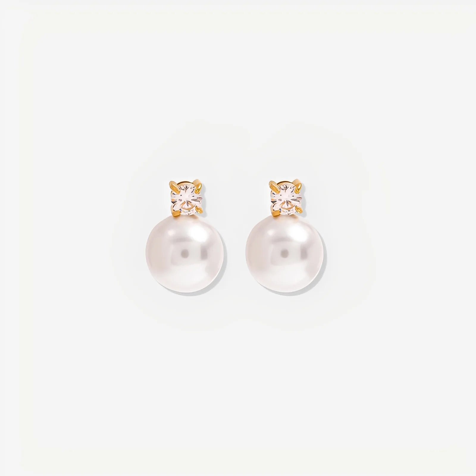 Pearl earrings with gold and crystal accents on a white background