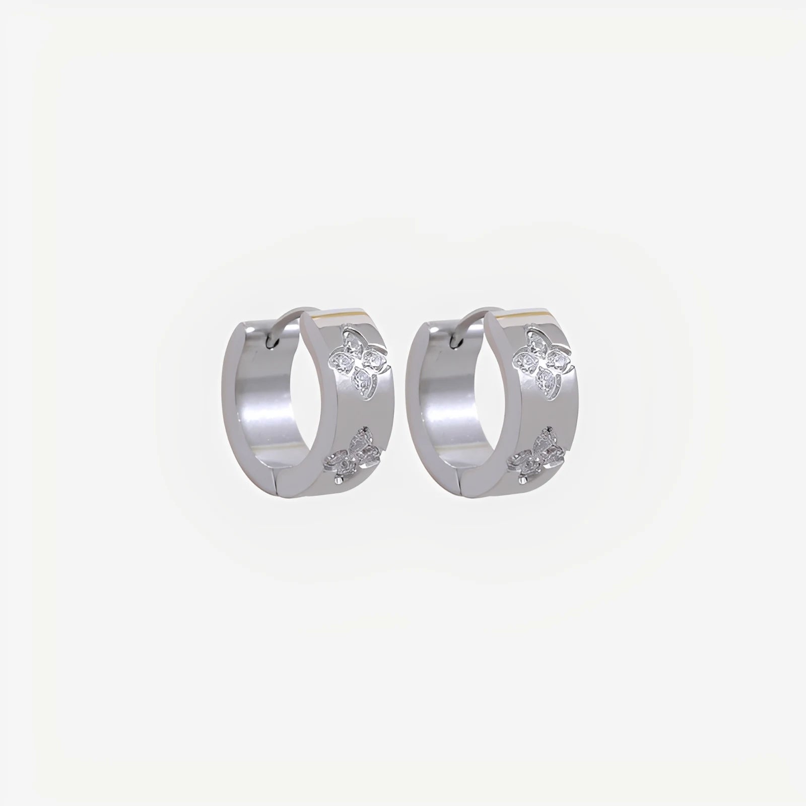 Silver hoop earrings with small round stones on a light gray background