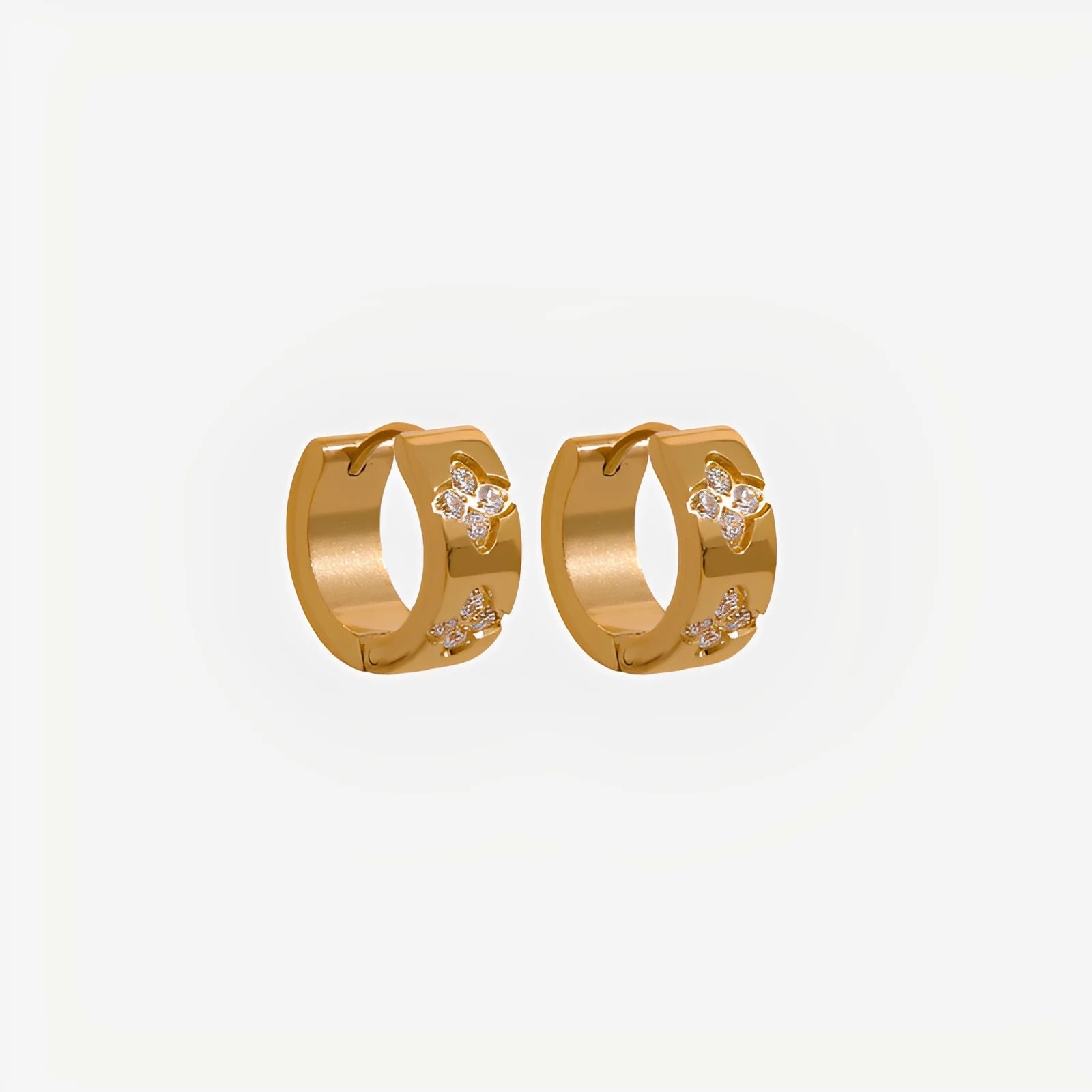Gold hoop earrings with floral designs on a light gray background