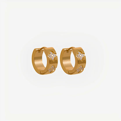 Gold hoop earrings with floral designs on a light gray background