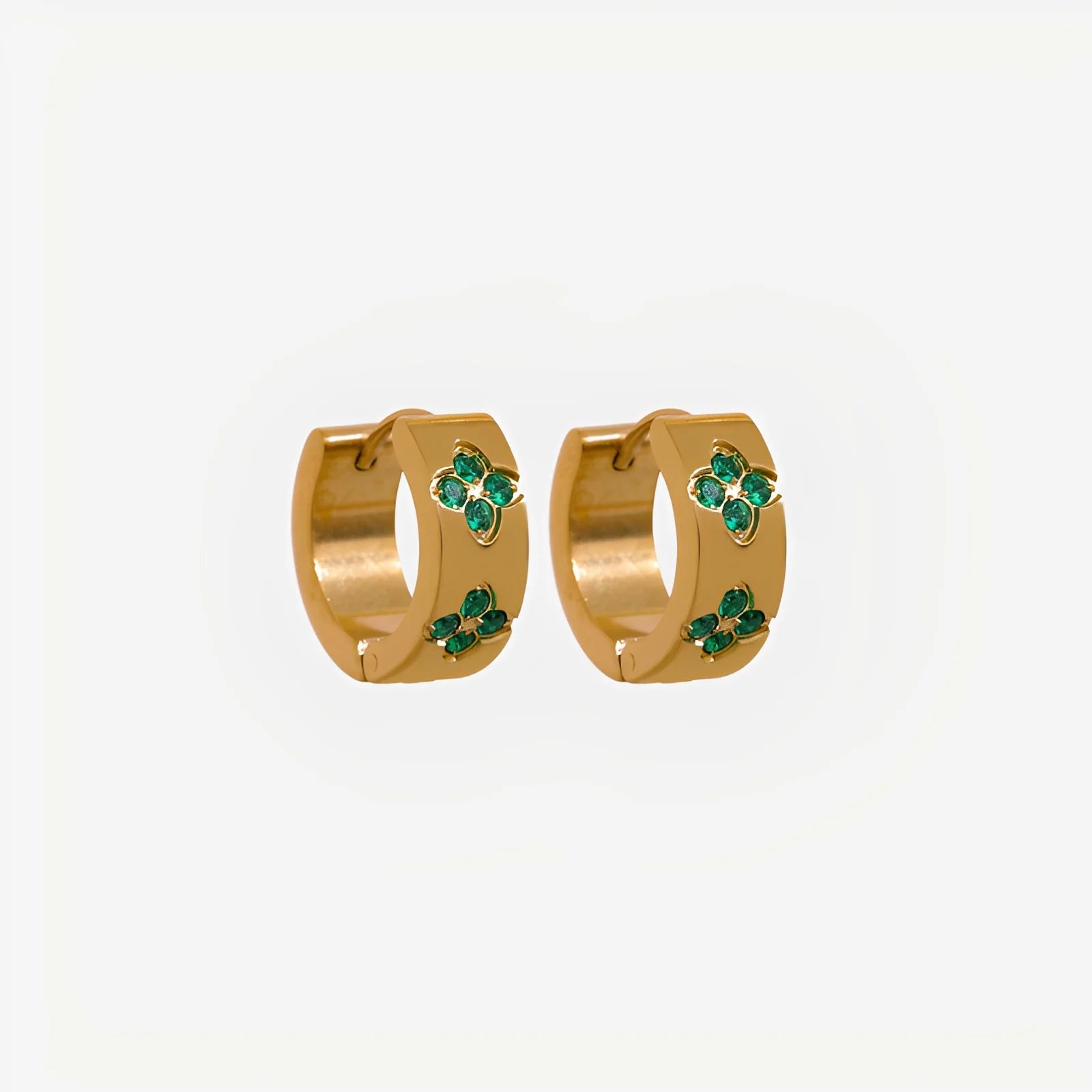 Gold hoop earrings with green gemstones on a light gray background