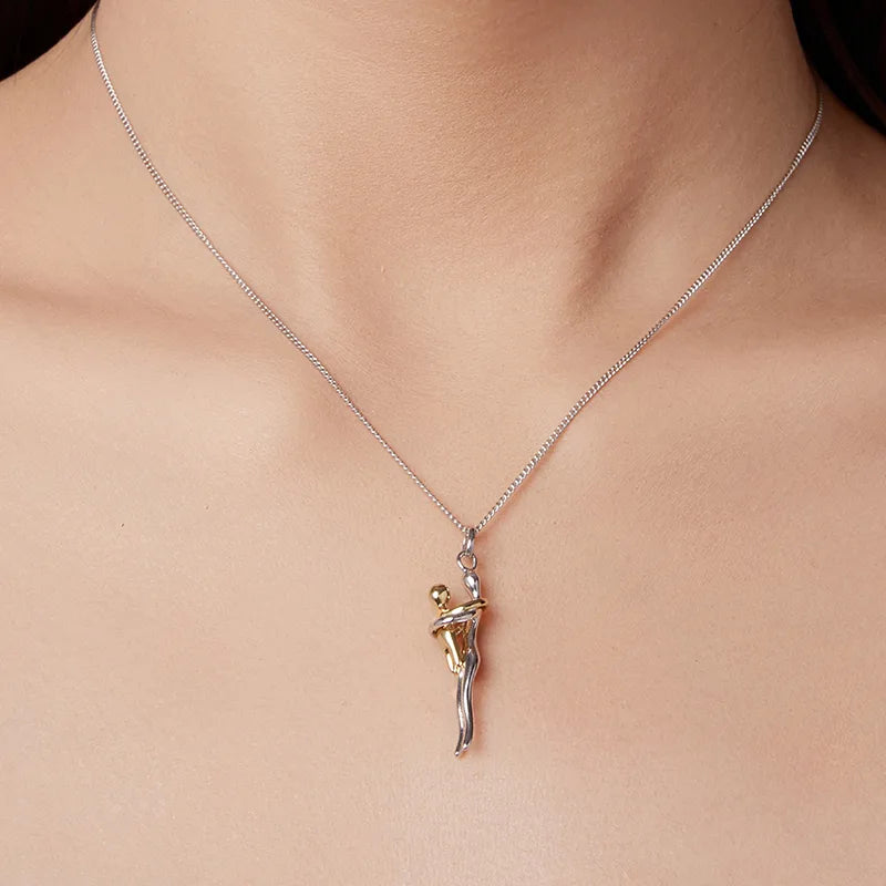 Necklace with a pendant featuring a gold and silver figure on a person's neck.