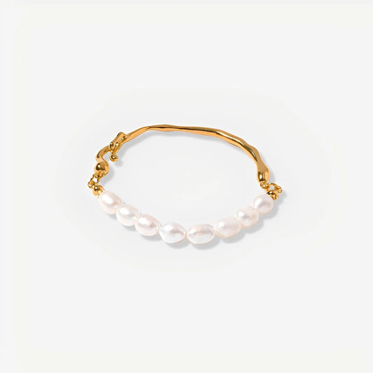 Gold bracelet with pearls on a light gray background
