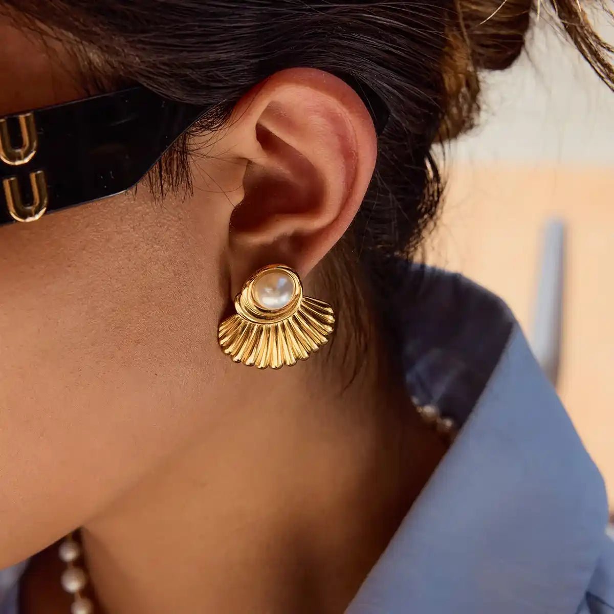 Close-up of a person wearing a gold earring with a pearl center.