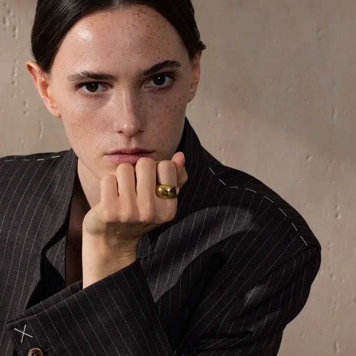 Person wearing a black pinstripe suit with a neutral background