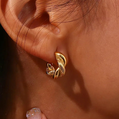 Close-up of a gold hoop earring on an ear with a blurred background