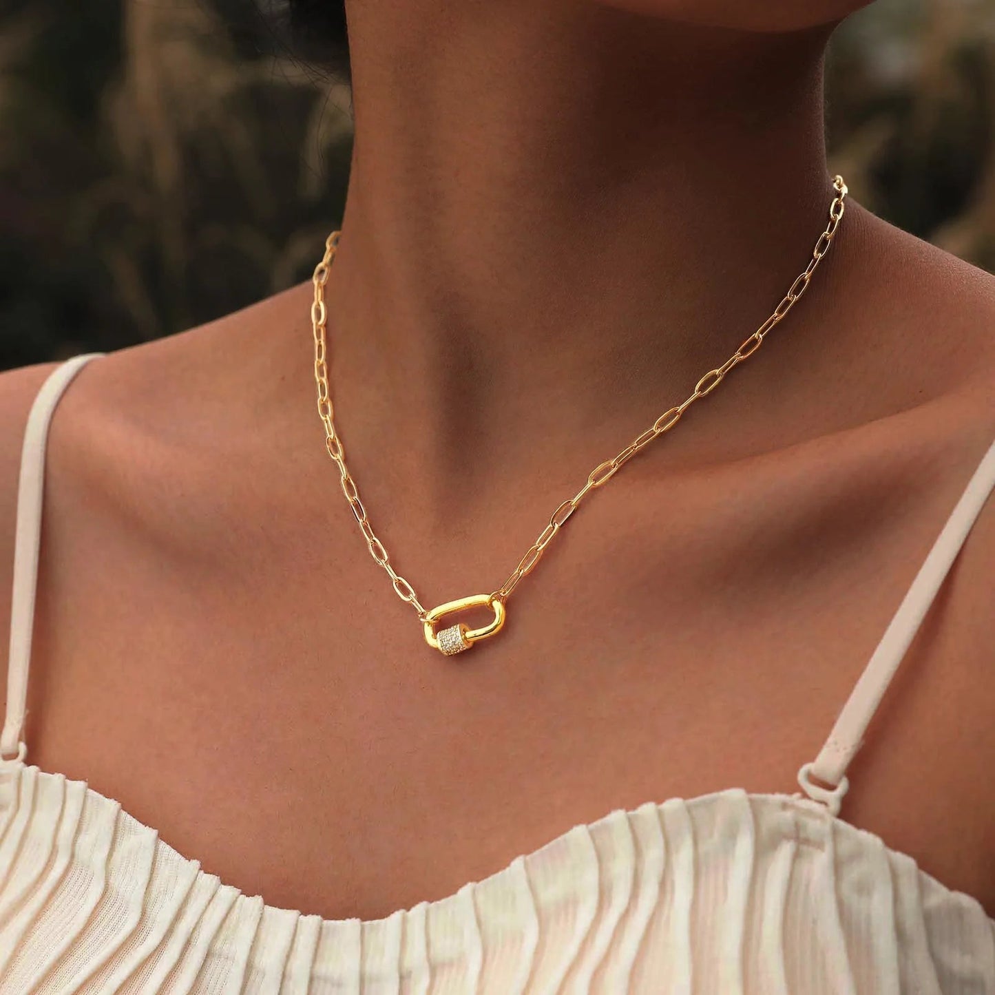 Gold chain necklace with a unique clasp on a person wearing a beige top.