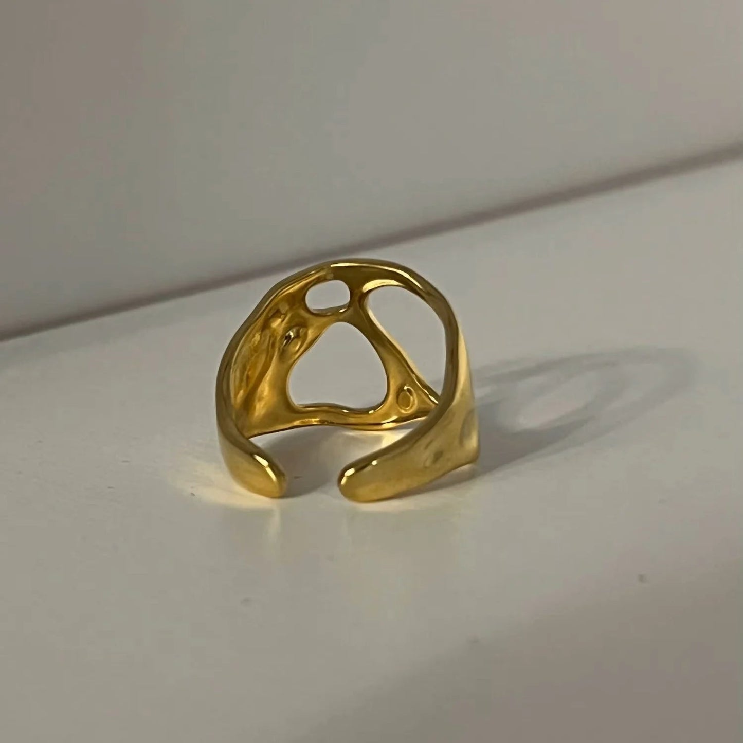 Gold ring with a unique design on a light gray background