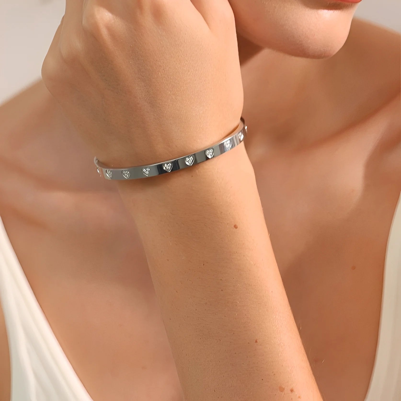 Silver bracelet with engraved design on a person's wrist against a neutral background