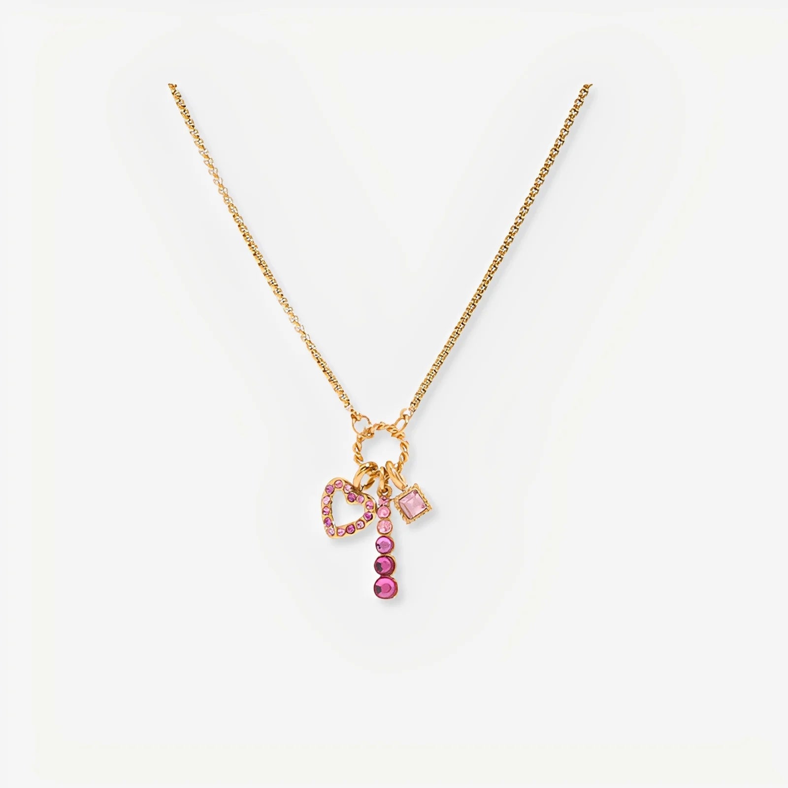 Gold necklace with pink and red charm on a white background