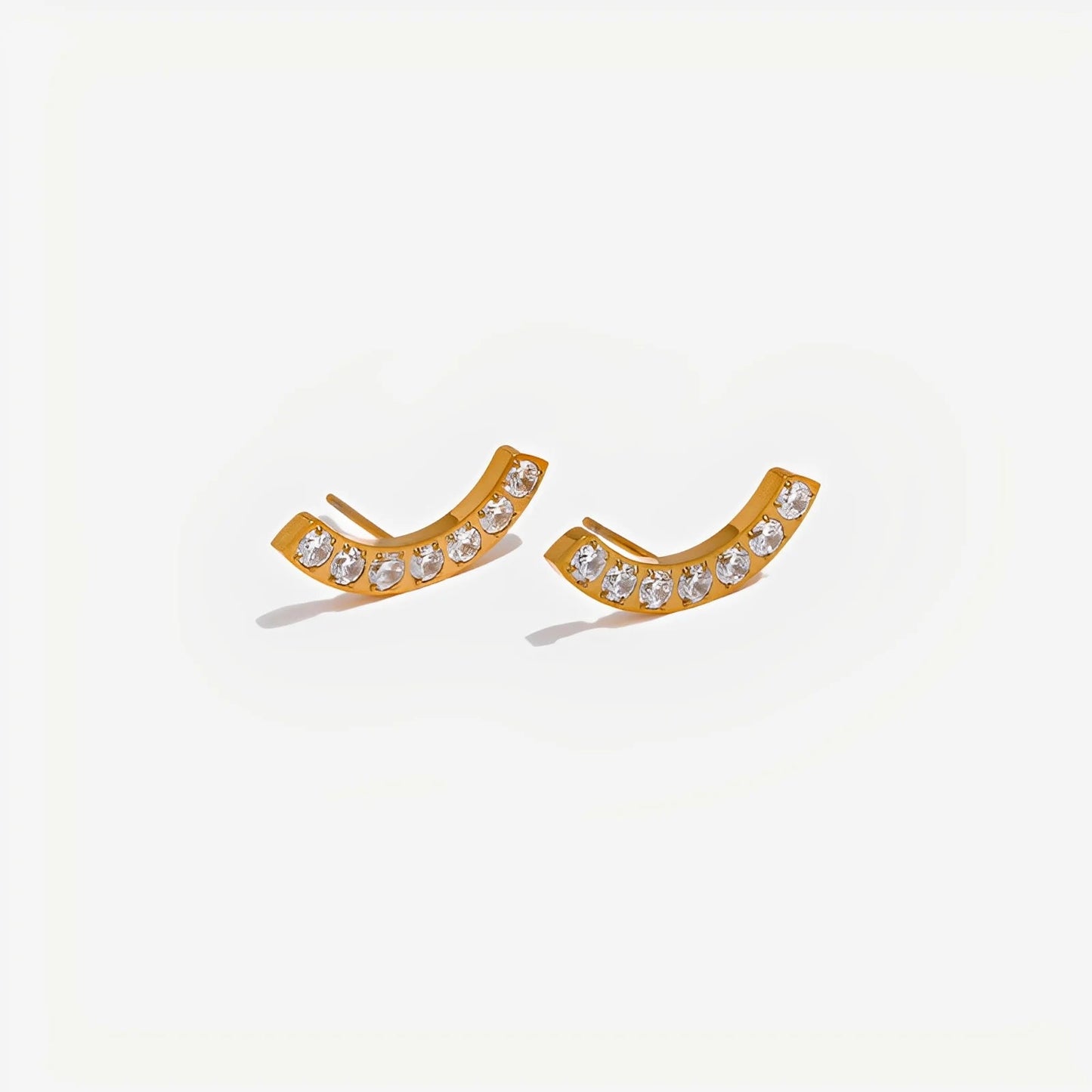 Gold earrings with clear stones on a light gray background