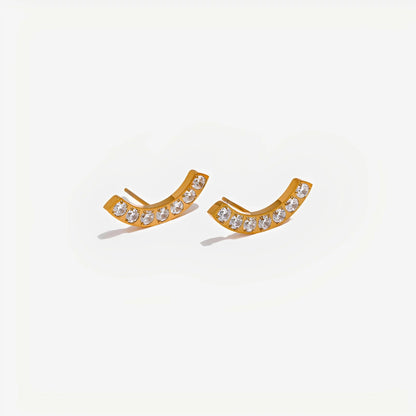 Gold earrings with clear stones on a light gray background