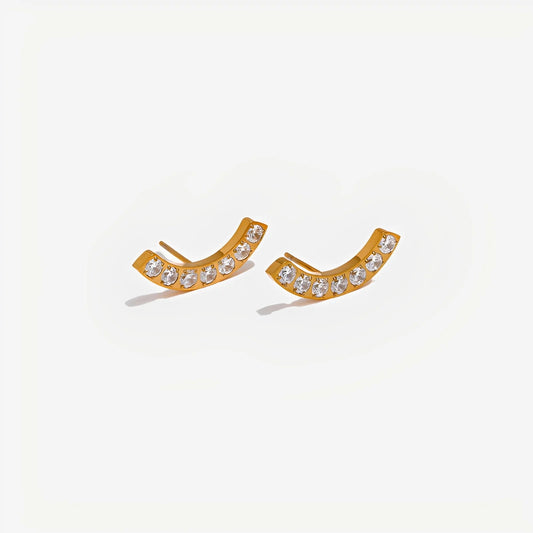 Gold earrings with clear stones on a light gray background