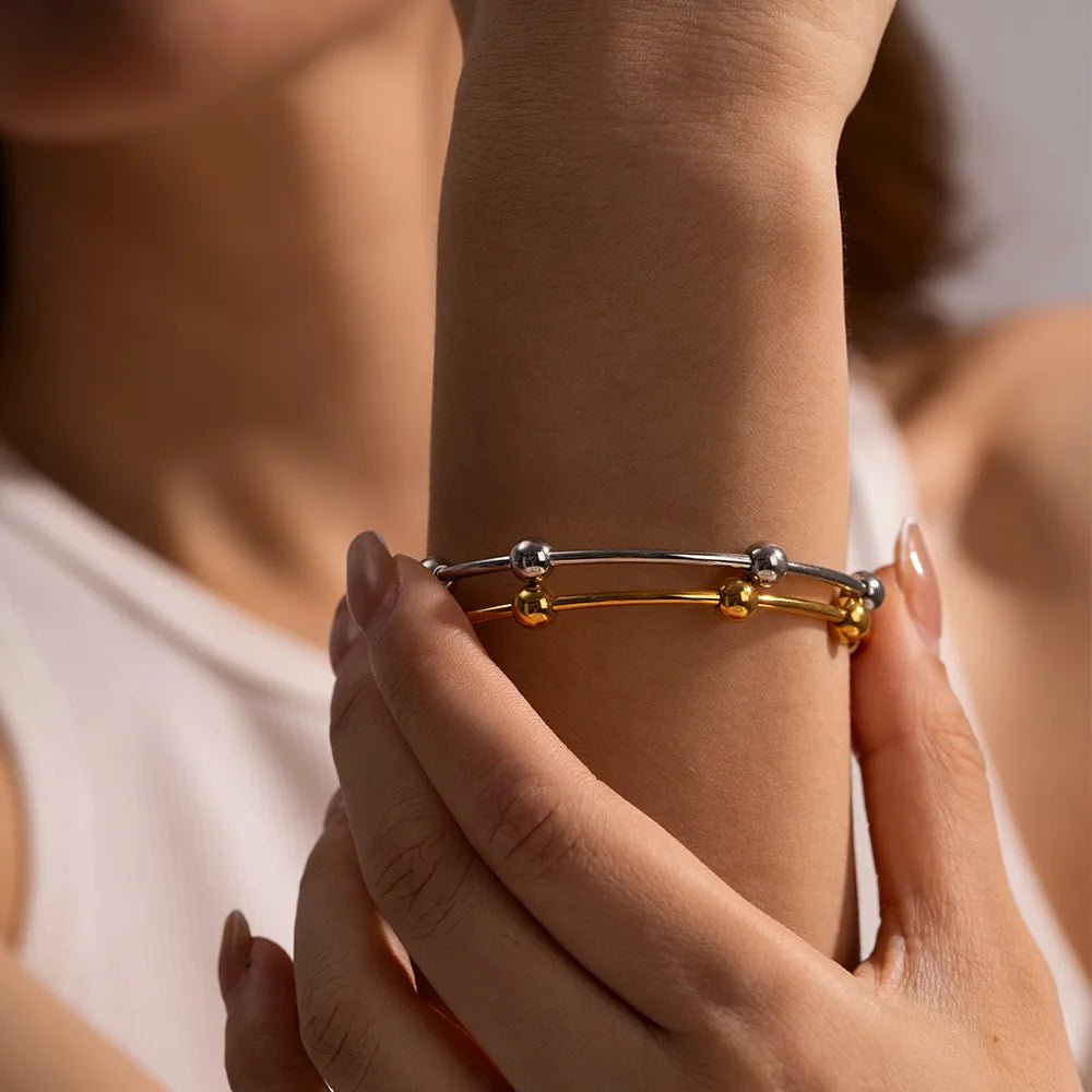 Close-up of a person wearing a gold and silver bracelet on a blurred background