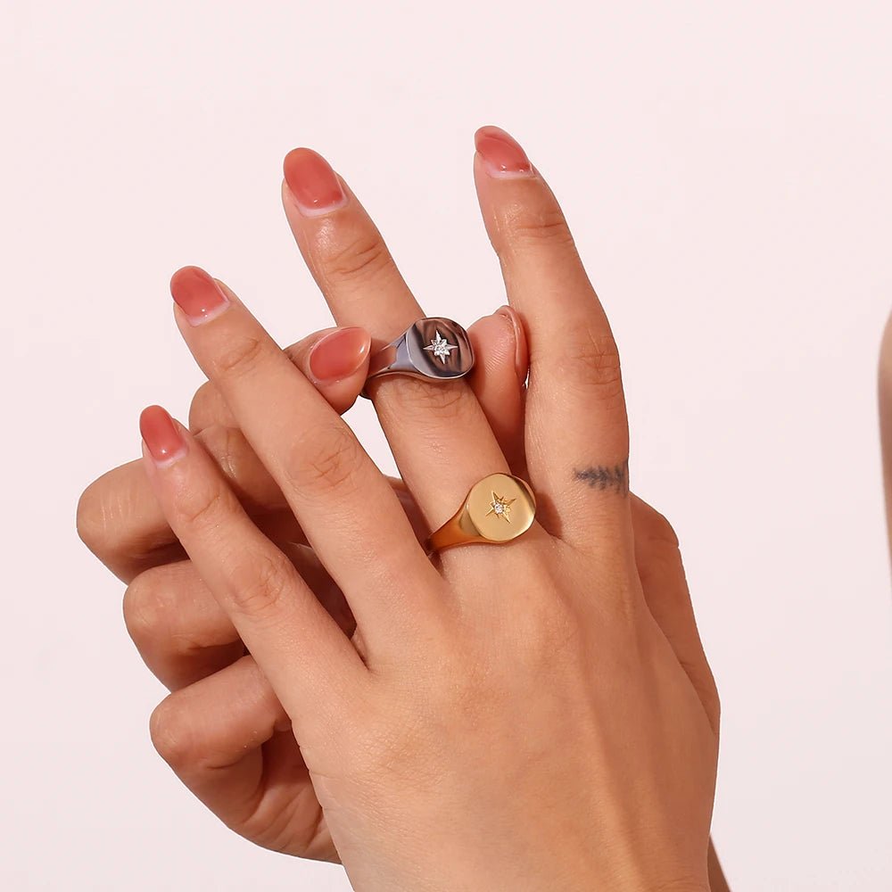 Hand wearing two rings on a light pink background