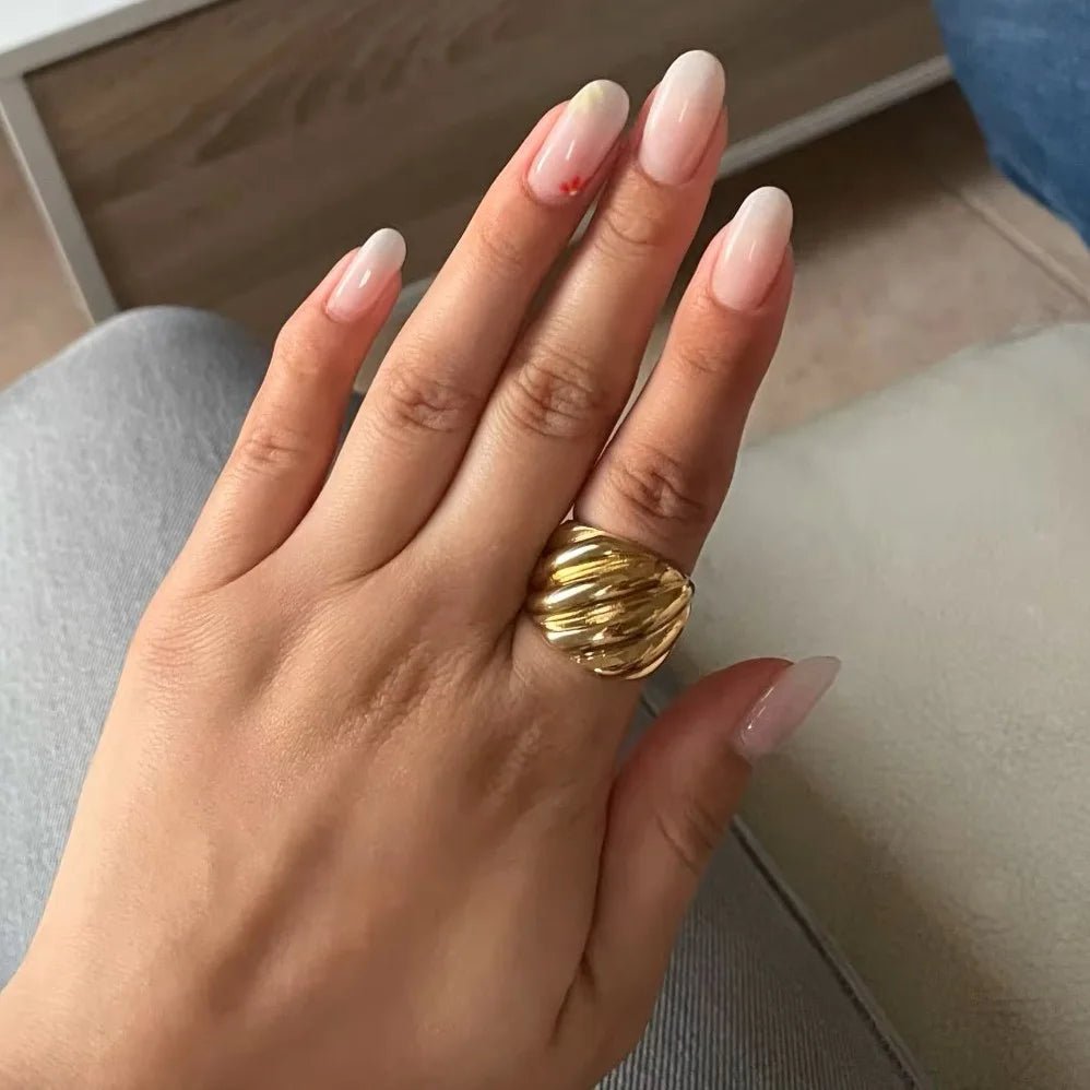 Hand with a gold ring on a neutral background