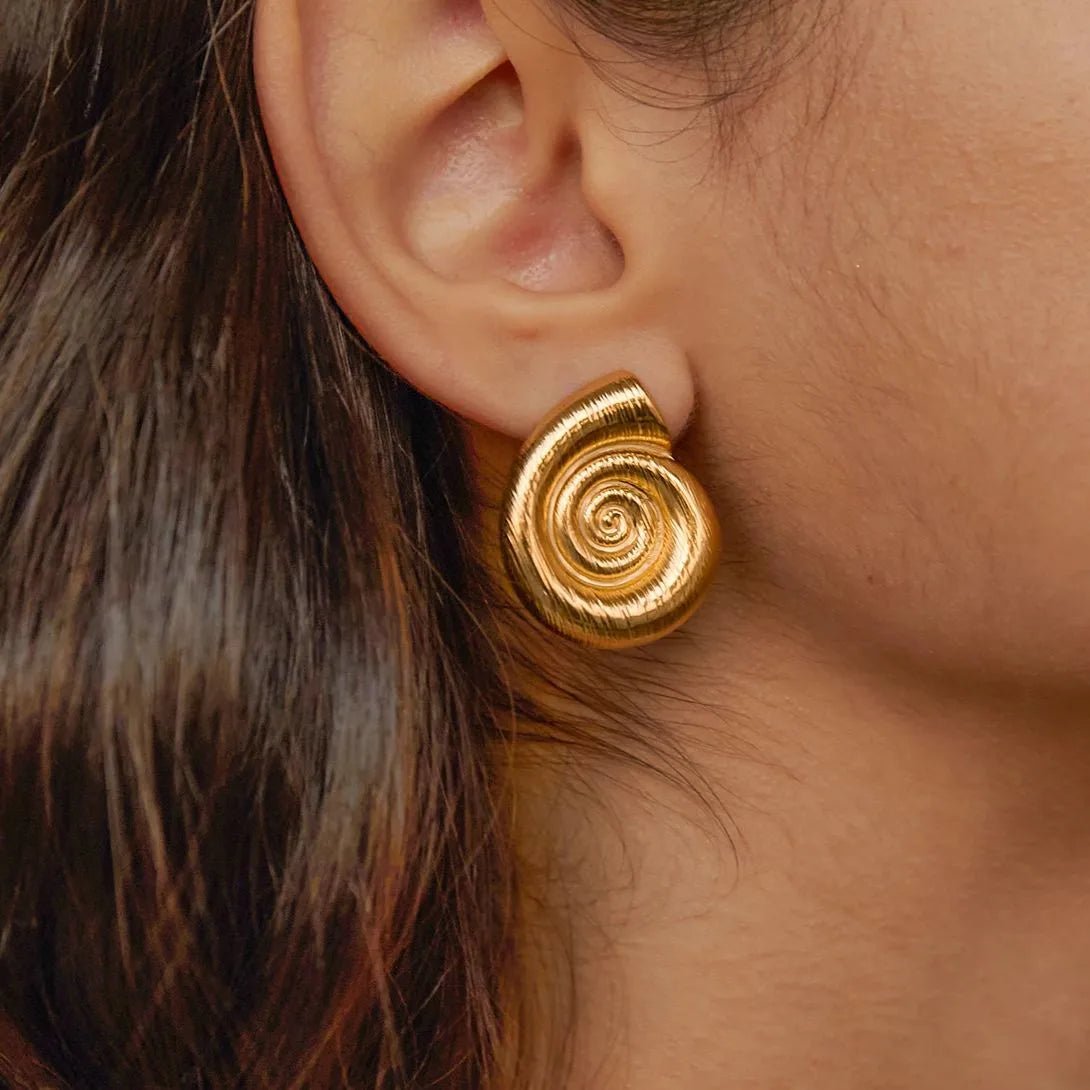Close-up of a person wearing gold spiral earrings.
