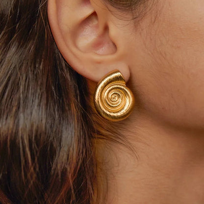 Close-up of a person wearing gold spiral earrings.