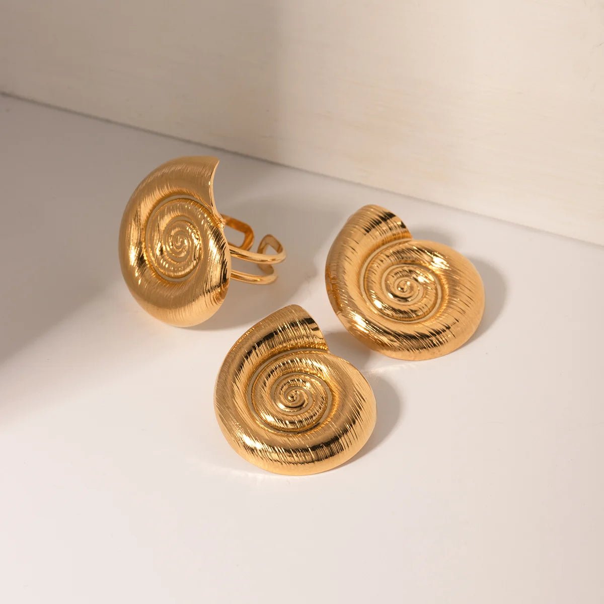 Gold shell-shaped cufflinks on a light beige background