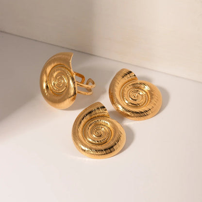Gold shell-shaped cufflinks on a light beige background