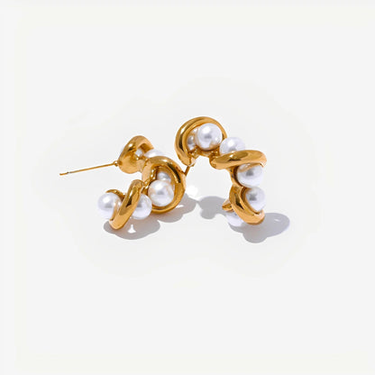 Gold earrings with pearl-like beads on a light beige background