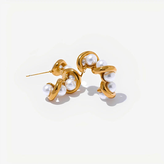 Gold earrings with pearl-like beads on a light beige background
