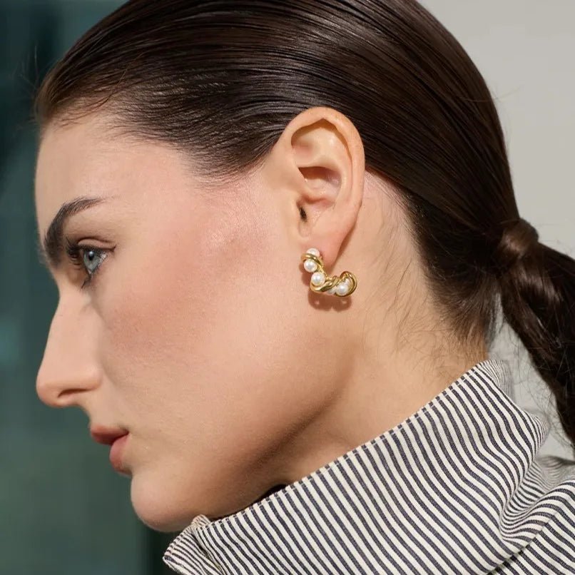 Close-up of a woman wearing a gold earring with pearls.