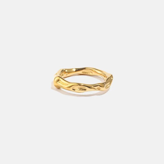 Gold ring with a wavy design on a light gray background